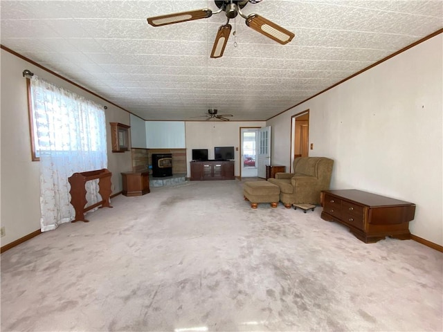 unfurnished living room featuring carpet flooring, a ceiling fan, crown molding, and baseboards