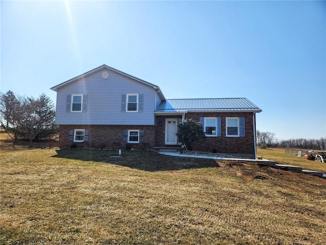 tri-level home featuring a front yard, brick siding, and metal roof