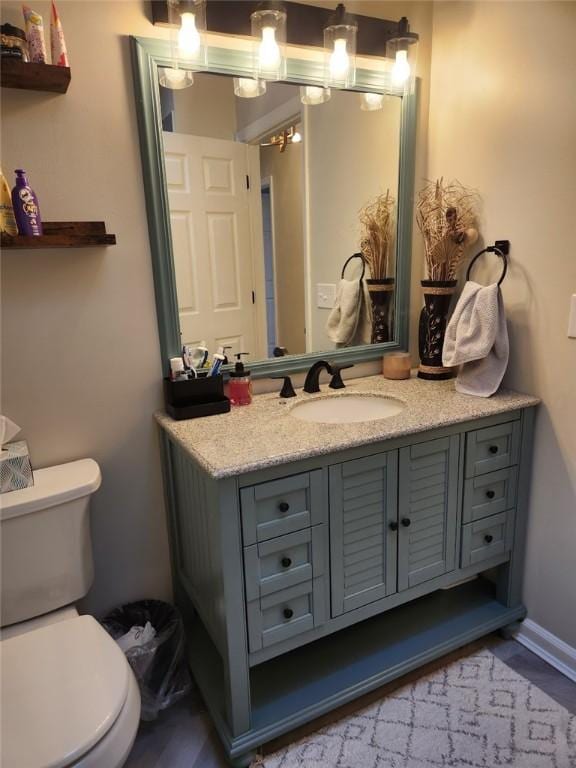 bathroom with toilet, vanity, and baseboards