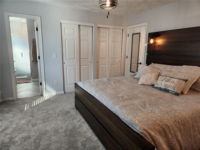 bedroom featuring carpet flooring, baseboards, ensuite bathroom, and multiple closets