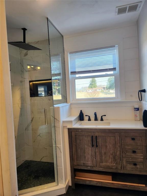 full bath with a marble finish shower, visible vents, and vanity