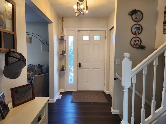 entryway with a chandelier, stairs, dark wood-type flooring, and baseboards