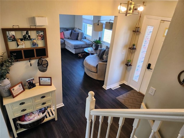 foyer entrance with a chandelier, visible vents, baseboards, and dark wood-style flooring