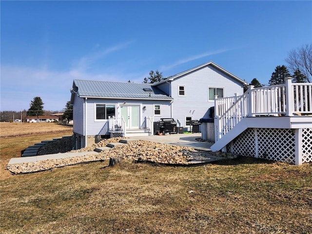 back of property with a wooden deck, a lawn, and metal roof