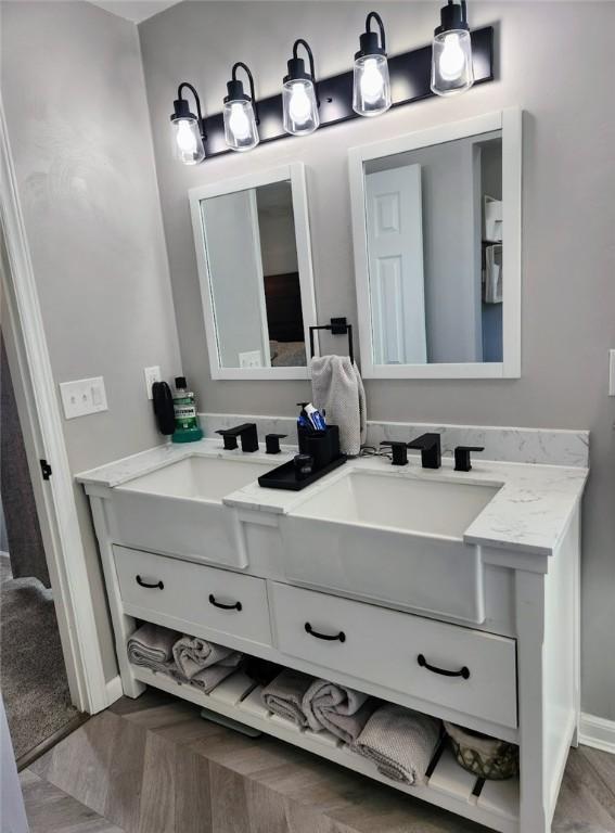 full bathroom featuring a sink, baseboards, and double vanity