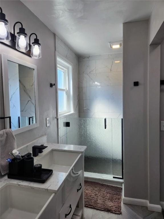 full bath featuring a shower stall, vanity, and baseboards