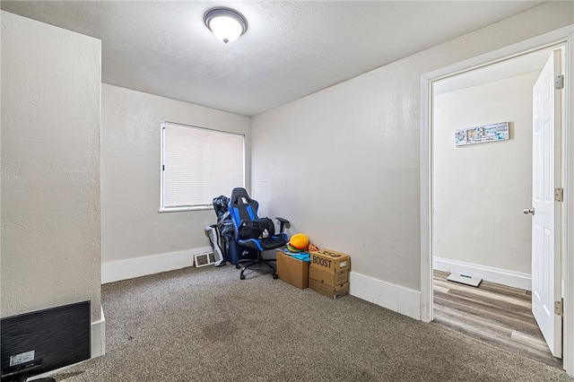 unfurnished office with visible vents, baseboards, carpet, and a textured ceiling