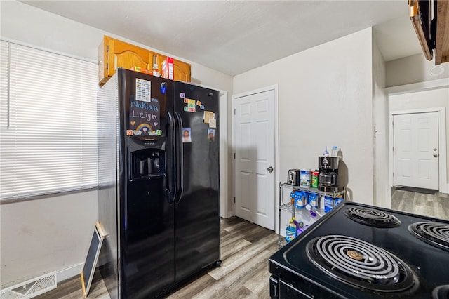 kitchen with visible vents, black appliances, light wood-type flooring, and baseboards