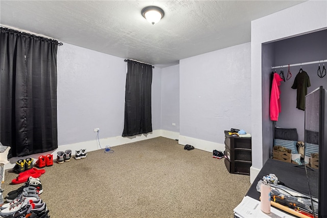 bedroom featuring carpet flooring, a textured ceiling, baseboards, and a textured wall