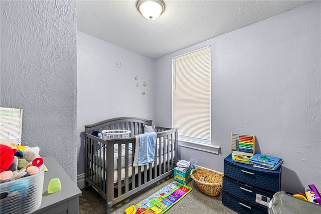 bedroom with a crib, carpet, and a textured wall