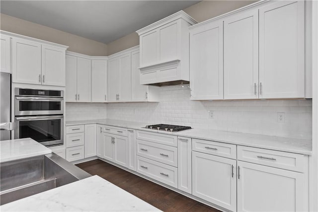 kitchen featuring decorative backsplash, white cabinets, dark wood-style floors, and stainless steel appliances