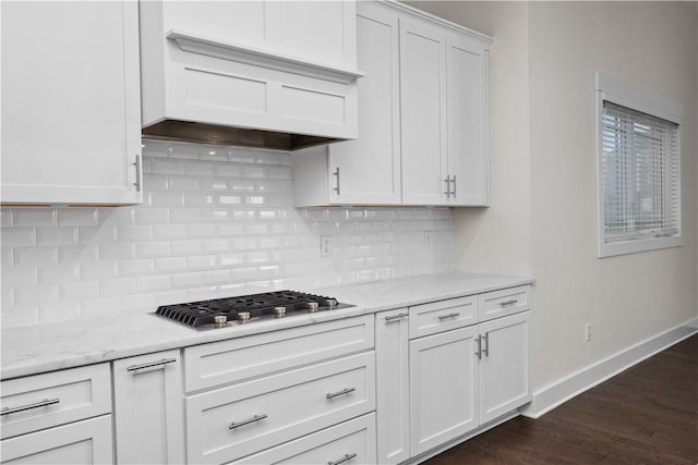 kitchen featuring baseboards, stainless steel gas cooktop, custom exhaust hood, dark wood-type flooring, and white cabinets