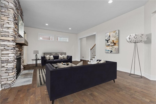 living room with dark wood finished floors, a fireplace, stairs, and baseboards