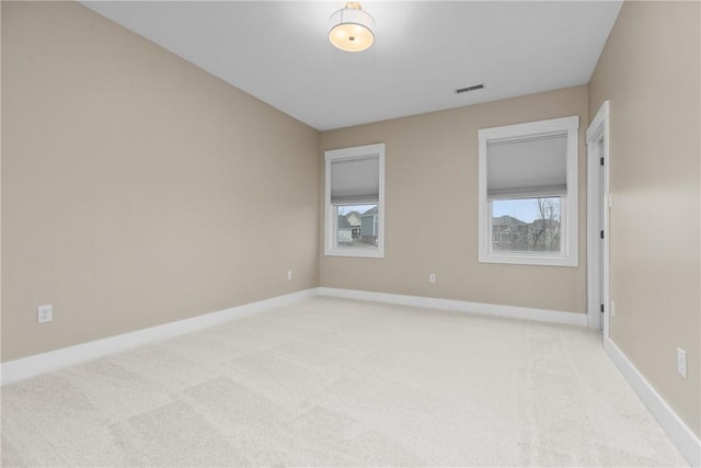 spare room with baseboards, visible vents, and light carpet