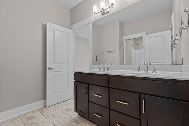 bathroom with double vanity, baseboards, and a sink