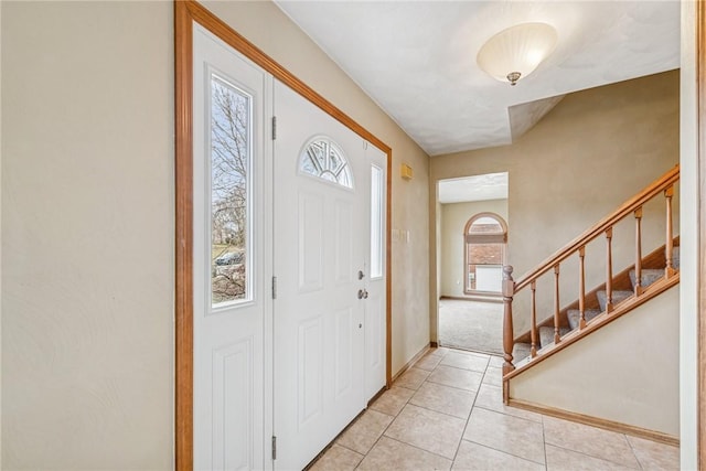 foyer with light tile patterned floors, stairs, and baseboards