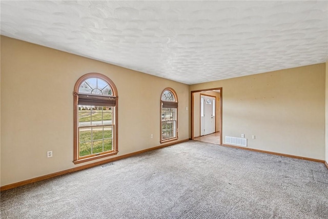 spare room with visible vents, baseboards, carpet, and a textured ceiling