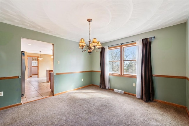 carpeted empty room with visible vents, baseboards, an inviting chandelier, and tile patterned flooring