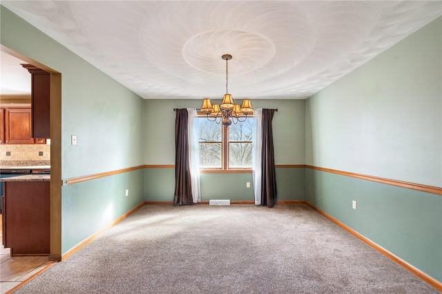 spare room with baseboards, light carpet, an inviting chandelier, and visible vents