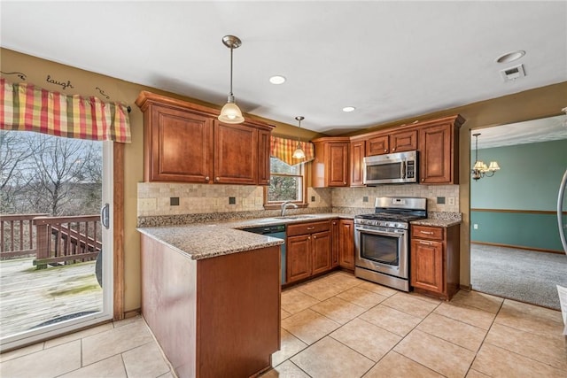 kitchen featuring visible vents, a sink, backsplash, appliances with stainless steel finishes, and a peninsula