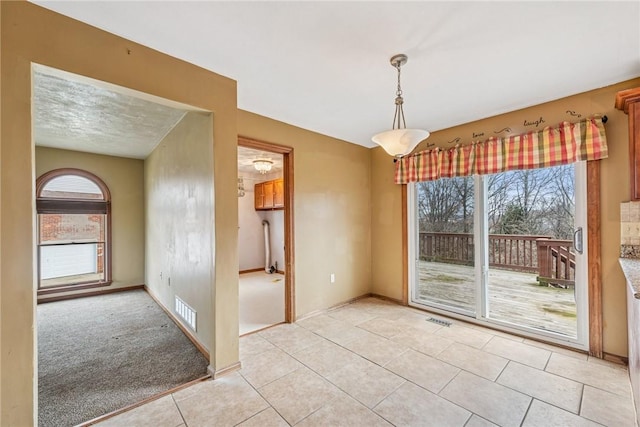 unfurnished dining area with a wealth of natural light, visible vents, baseboards, and light tile patterned floors