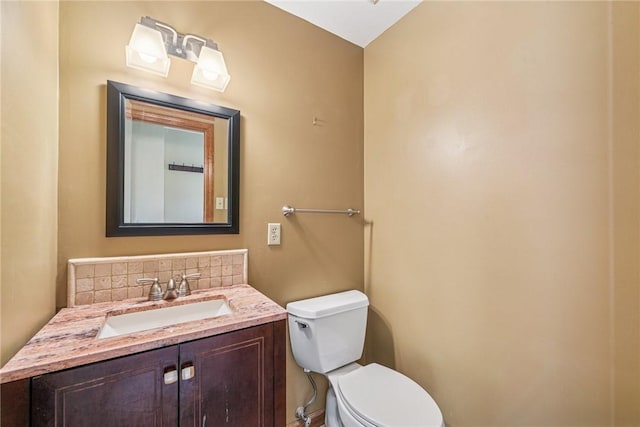 bathroom with decorative backsplash, toilet, and vanity