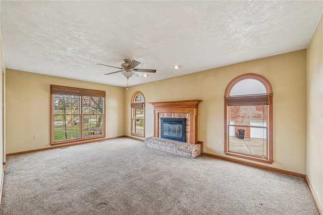 unfurnished living room featuring a fireplace, baseboards, carpet floors, and a textured ceiling