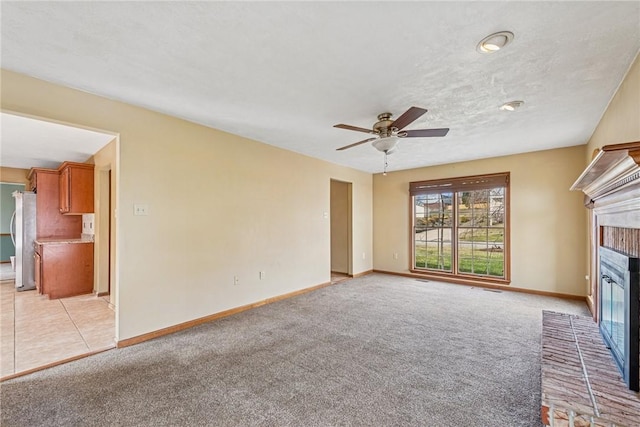 unfurnished living room with baseboards, light carpet, and a brick fireplace