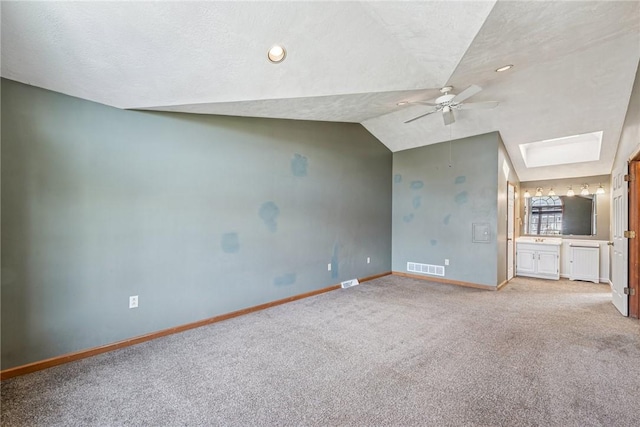 interior space with visible vents, lofted ceiling with skylight, radiator, baseboards, and light colored carpet