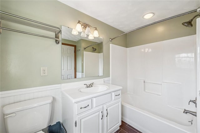 full bathroom featuring a wainscoted wall, toilet, vanity, wood finished floors, and washtub / shower combination