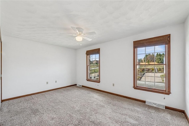 empty room with visible vents, baseboards, a ceiling fan, and carpet flooring