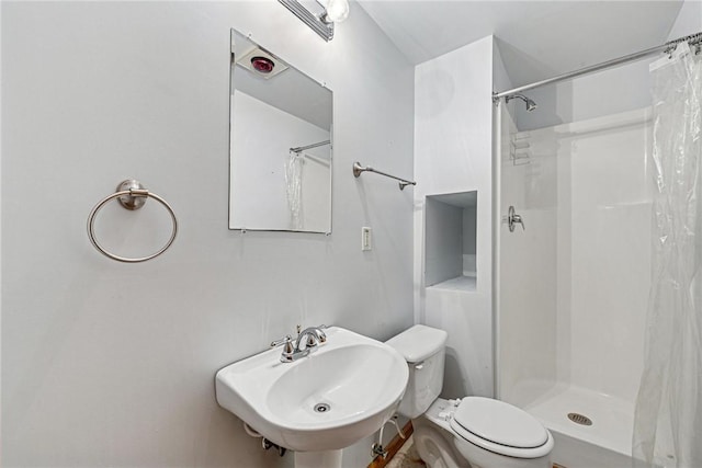 full bath featuring toilet, a stall shower, and a sink