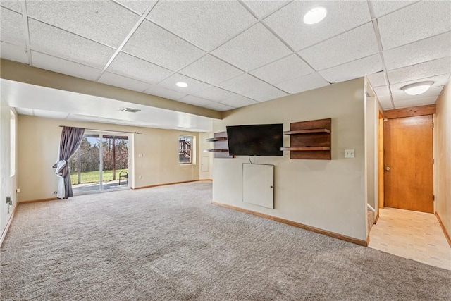 unfurnished living room featuring carpet flooring, a paneled ceiling, and baseboards