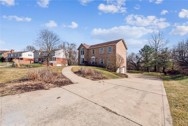 view of front of property with a front lawn, a residential view, brick siding, and driveway