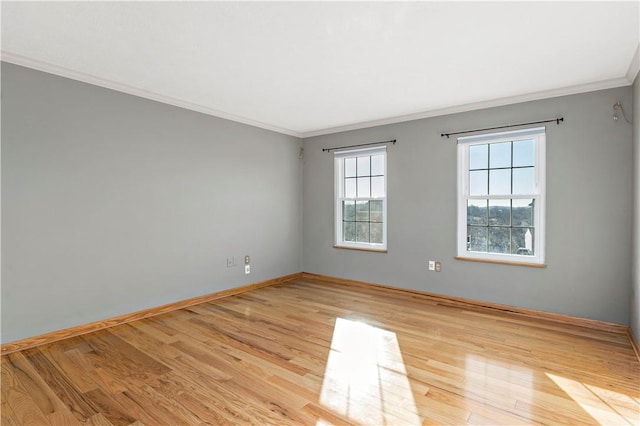 empty room featuring light wood-type flooring, baseboards, and ornamental molding