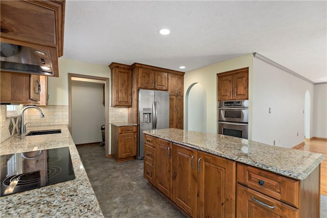 kitchen featuring arched walkways, light stone countertops, stainless steel appliances, and a sink