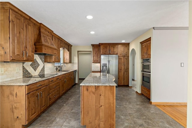 kitchen featuring premium range hood, a sink, a kitchen island, stainless steel appliances, and arched walkways