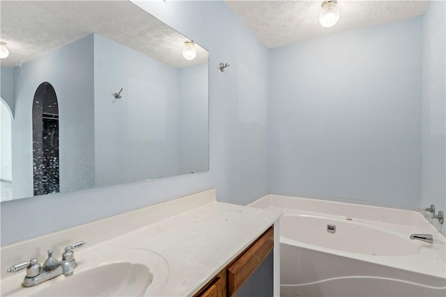 bathroom with a bath, a textured ceiling, and vanity