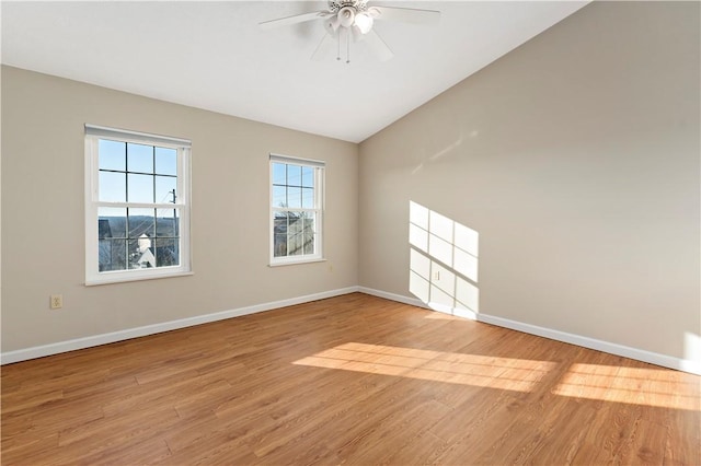 spare room with lofted ceiling, light wood-type flooring, and baseboards