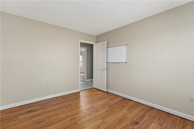 empty room featuring baseboards and light wood finished floors