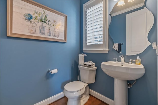 half bathroom featuring baseboards, toilet, and wood finished floors