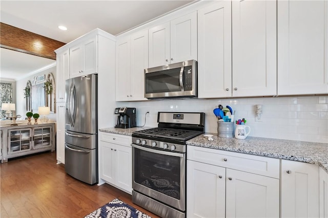 kitchen with tasteful backsplash, dark wood finished floors, light stone counters, appliances with stainless steel finishes, and white cabinetry