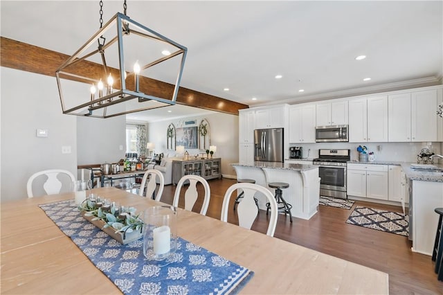 dining room featuring dark wood finished floors, an inviting chandelier, beamed ceiling, and recessed lighting