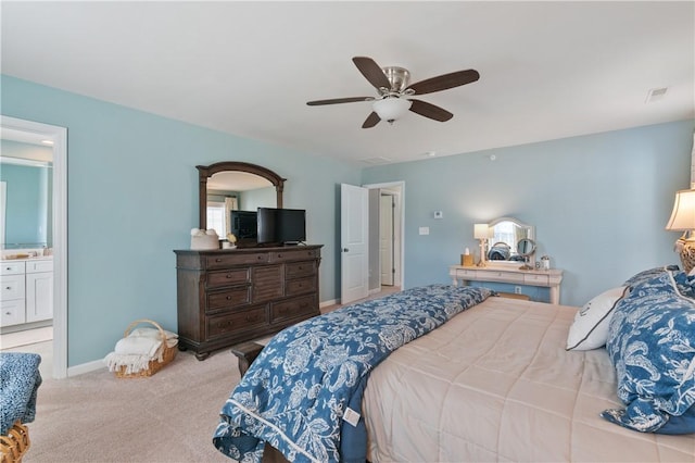 carpeted bedroom with baseboards, ensuite bath, and a ceiling fan