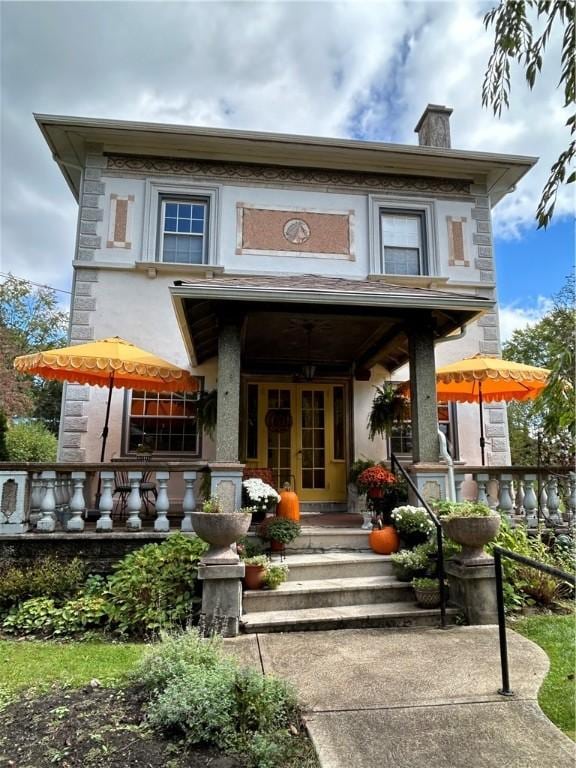 rear view of property featuring french doors, a chimney, and stucco siding