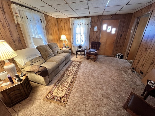 carpeted living area with wooden walls and a paneled ceiling