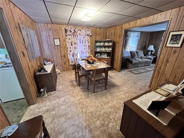 dining space featuring washer / dryer, carpet, wood walls, and a paneled ceiling