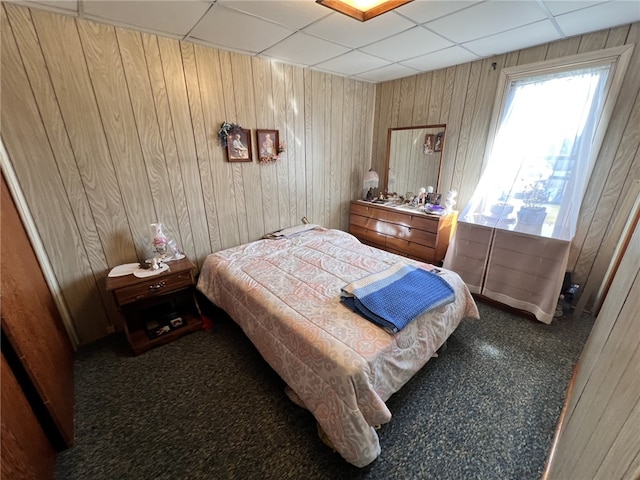 bedroom featuring wooden walls, a paneled ceiling, and carpet