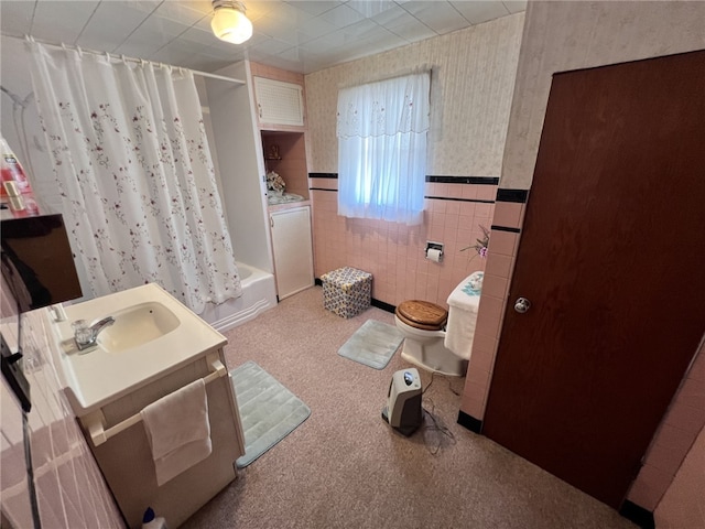 bathroom with a wainscoted wall, shower / bath combo with shower curtain, toilet, tile walls, and wallpapered walls