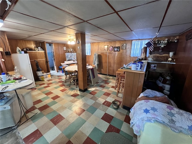 dining room with tile patterned floors, a drop ceiling, and wooden walls